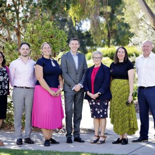 Photo of members of the digital team standing in front of a tree