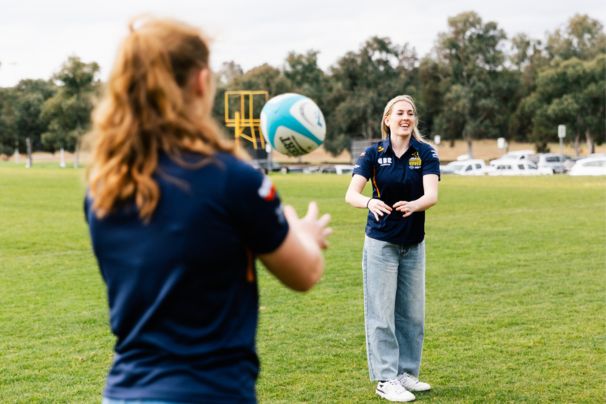 Lily Bone and April Downey tossing a football