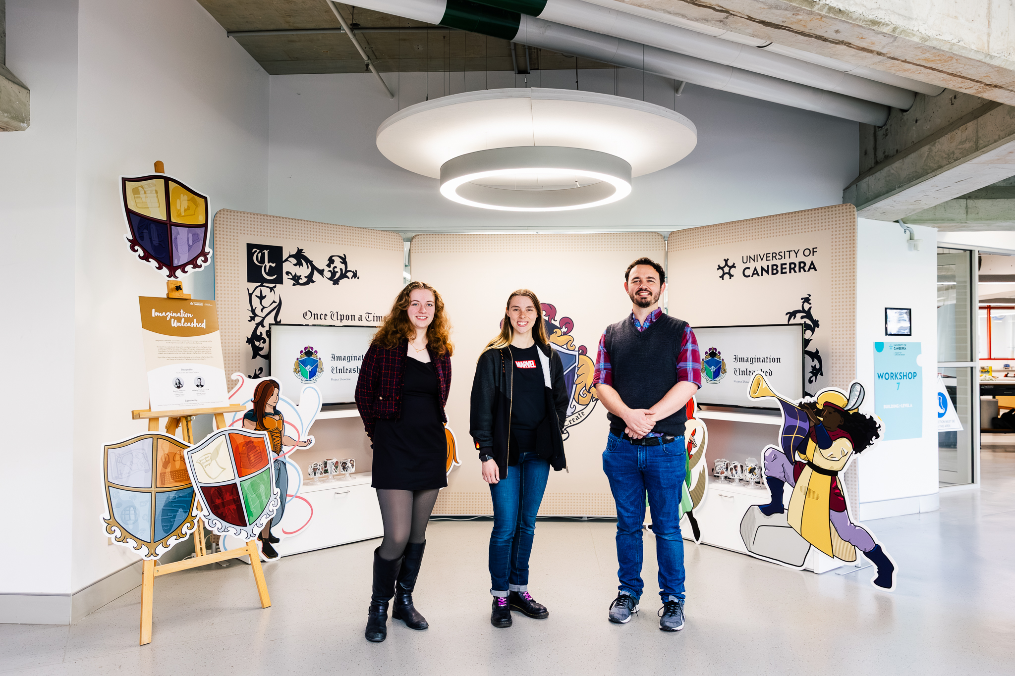 Three people standing infront of University of Canberra booth