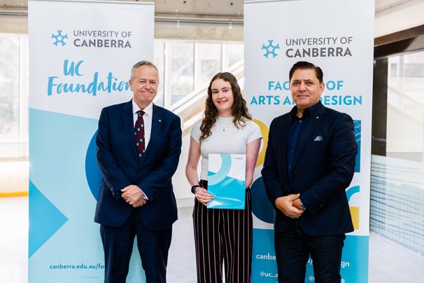 Natalie Millerd (middle) with Vice-Chancellor Bill Shorten on the left and UC Council Member Medy Hassan on the right - standing in front of University of Canberra banners