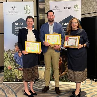 Three people stand side-by-side holding certificates