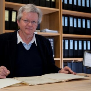 Dr Peter Copeman sits at a desk in his office