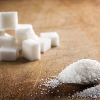 Sugar cubes sit in a bowl and on a spoon