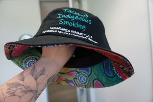 Black bucket hat which says Tackling Indigenous Smoking; Winnunga Nimmityjah Aboriginal Health and Community Services