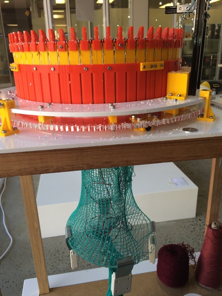 A digitally printed knitting machine from Estonia, made out of bright orange and yellow plastic.
