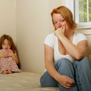 A single mum and her daughter sit on a bare mattress