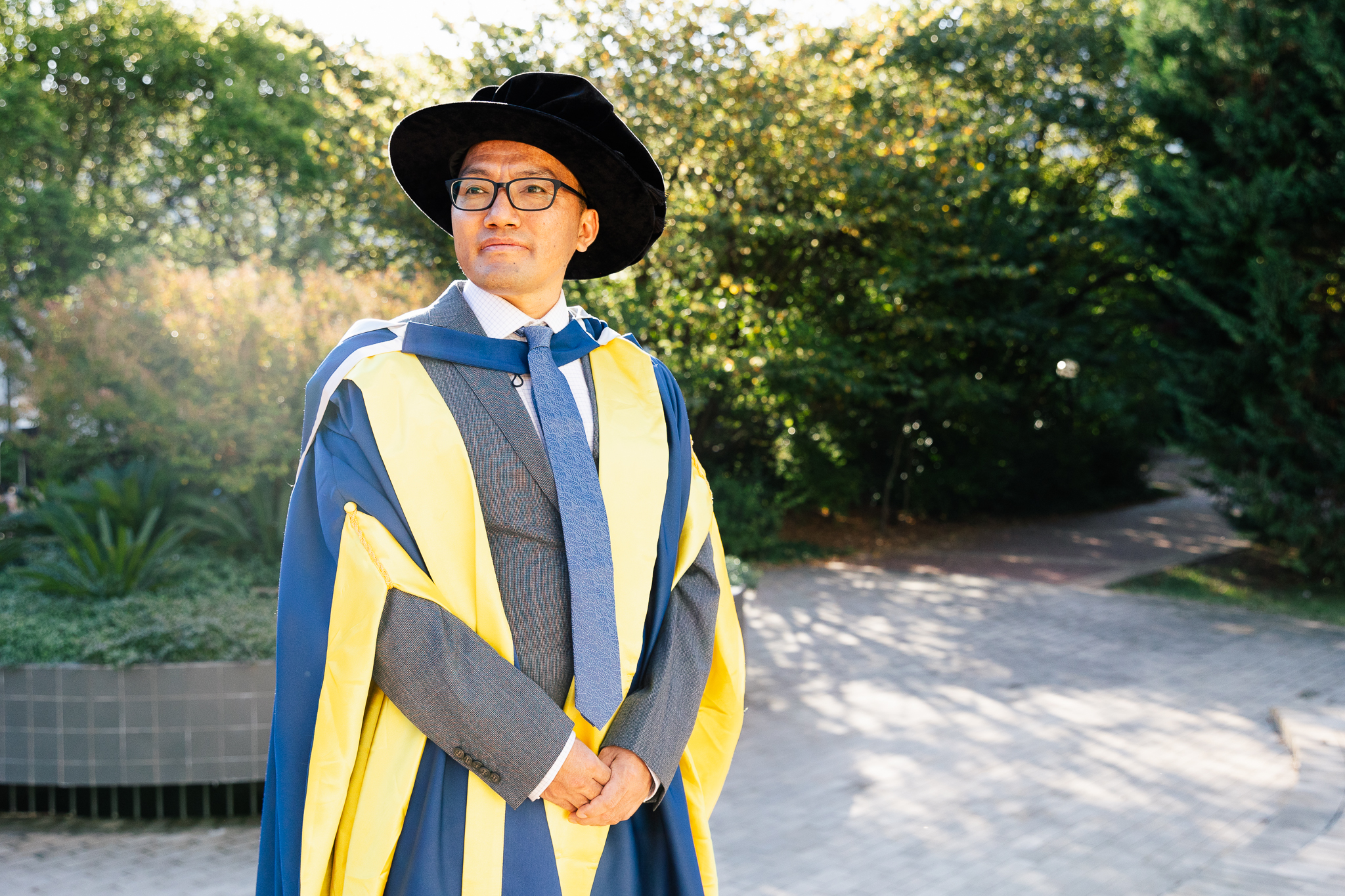 Man in graduation regalia poses for a photo