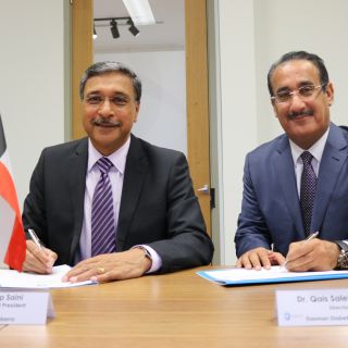 Professor Deep Saini and Dr Qais Saleh AL-Duwairi sign the MOU document with Australian and Kuwaiti flags on their desk