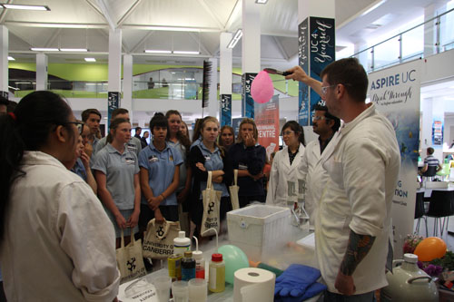 High school students at the science table watching how liquid nitrogen affects different objects at the UC 4 Yourself Expo