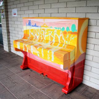 Multi-coloured piano against wall with Canberra written on it