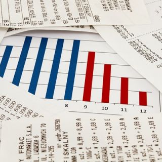 A graph showing savings dips into the red as a pile of bills grows.
