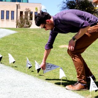 A staff member places a flag in the ground to support White Ribbon Day