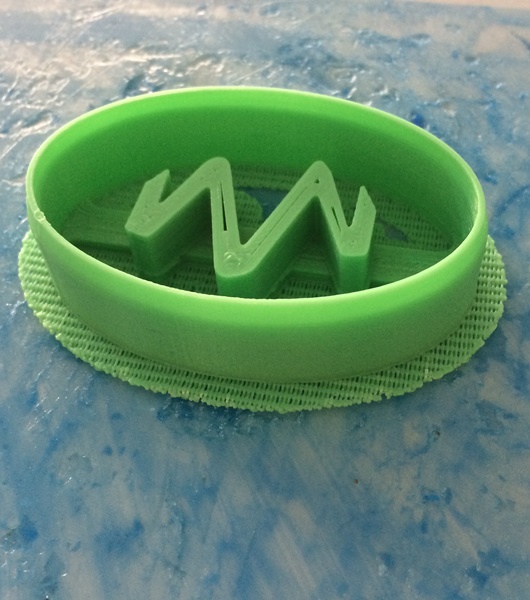 A bright green cookie cutter using the stylised M which appears in the Mobile Makers logo.