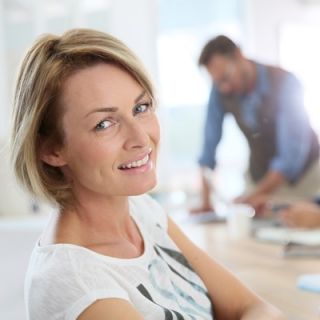 A woman sits in front of her laptop while colleagues work in the background