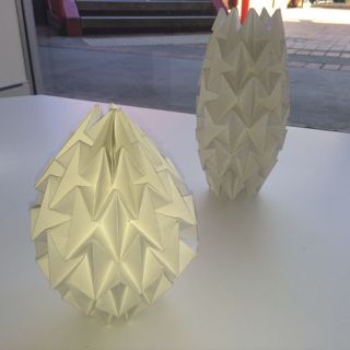 Lampshades made of folded white paper, featuring intricately folded shapes.