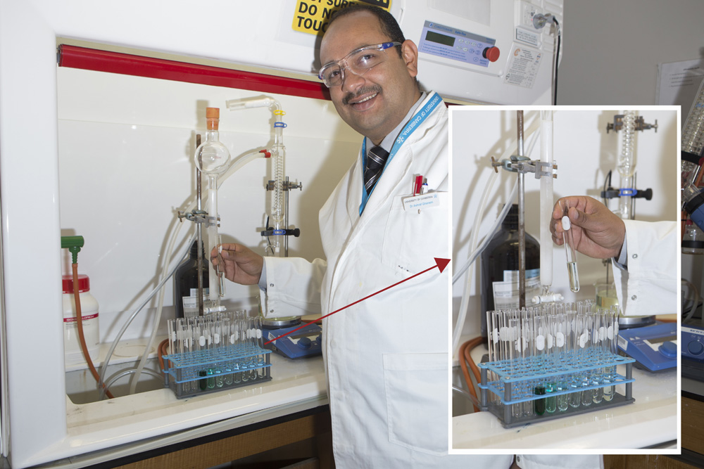Dr Ghanem is standing beside the glassware which he uses to conduct column chromatography refinement of his catalyst, inset image shows the refined solution in a test tube.
