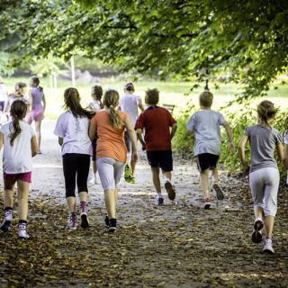 A group of primary school students running along a footpath