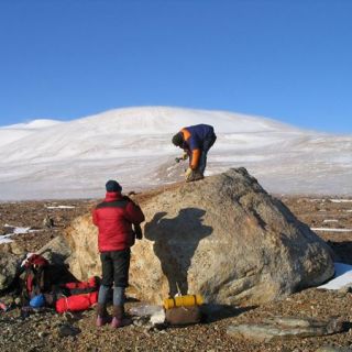 Dr Duanne White takes samples from a large boulder in Antarctica