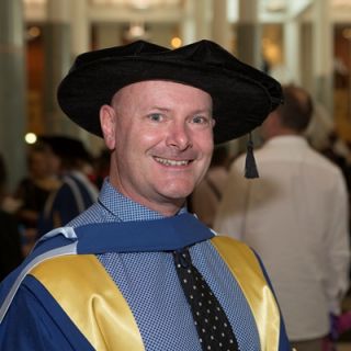 Dr Rob Stanton at his graduation ceremony decked out in his gown and bonnet