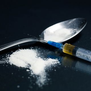 A needle and syringe, spoon and white powder