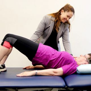 Kellie Toohey helps a woman stretch during the Cancer Rehabilitation exercise program for cancer 