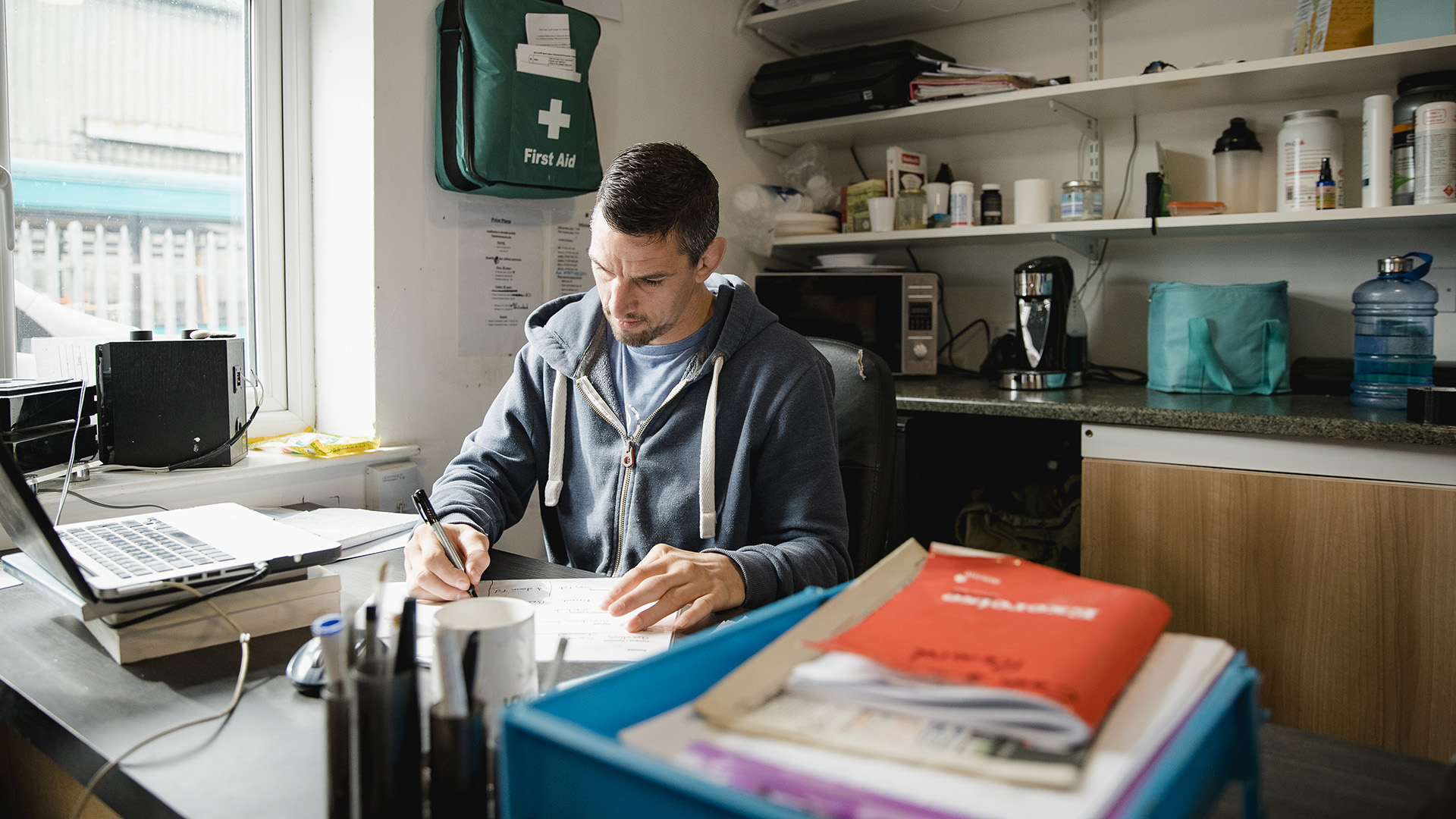 Trainer filling out administrative paperwork in an office at UC.