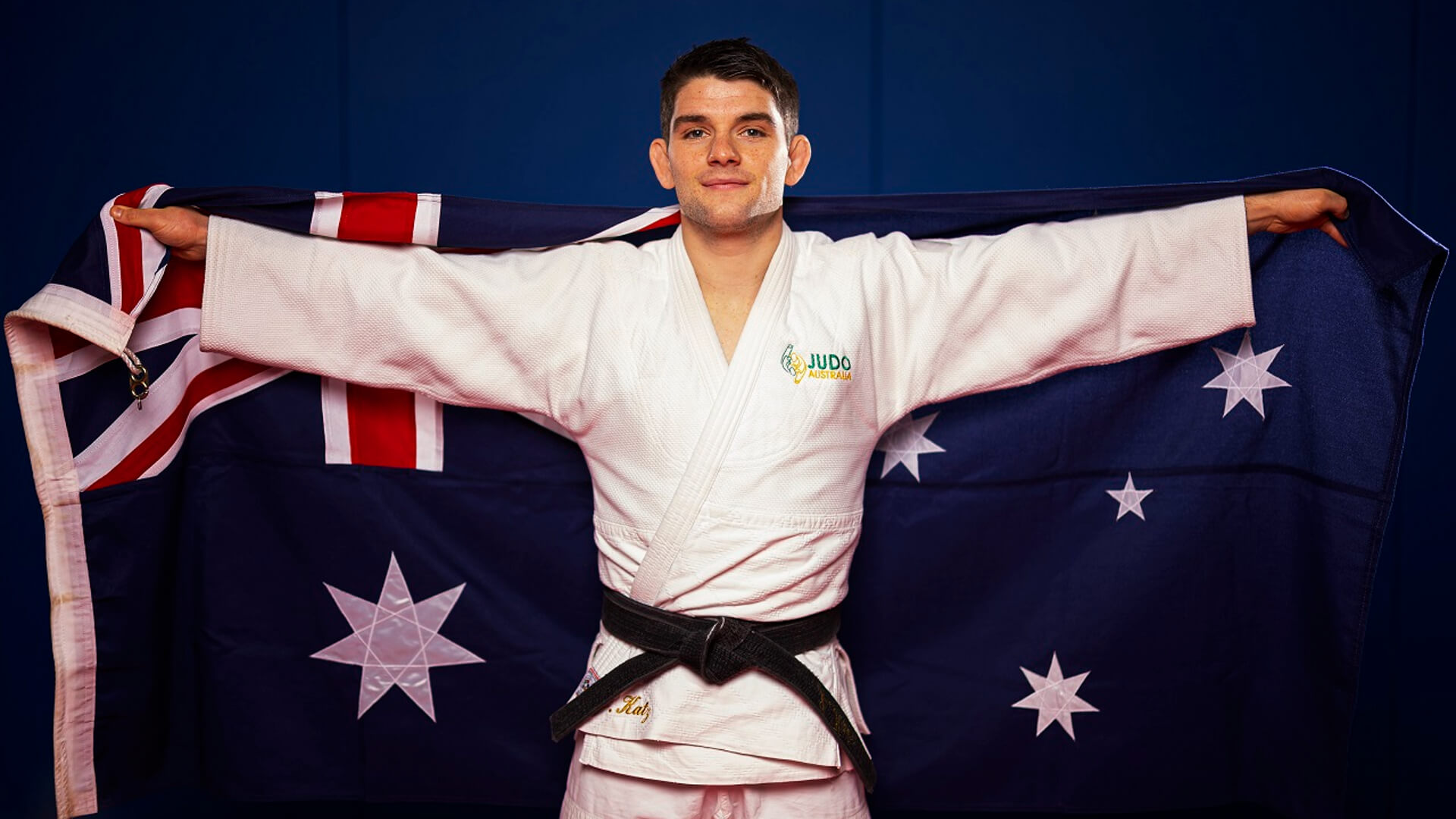 UC student and elite athlete Josh Katz wearing judogi holding Australian flag
