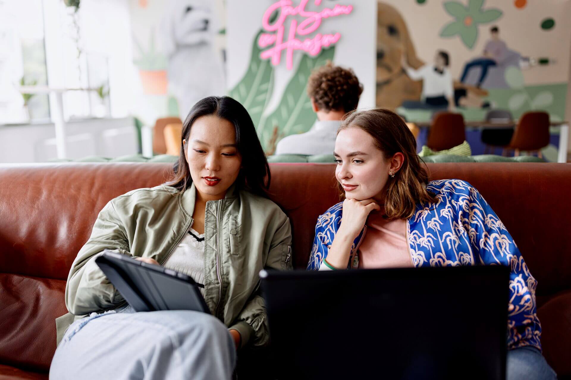 Two women studying a Bachelor of Business degree looking at a tablet