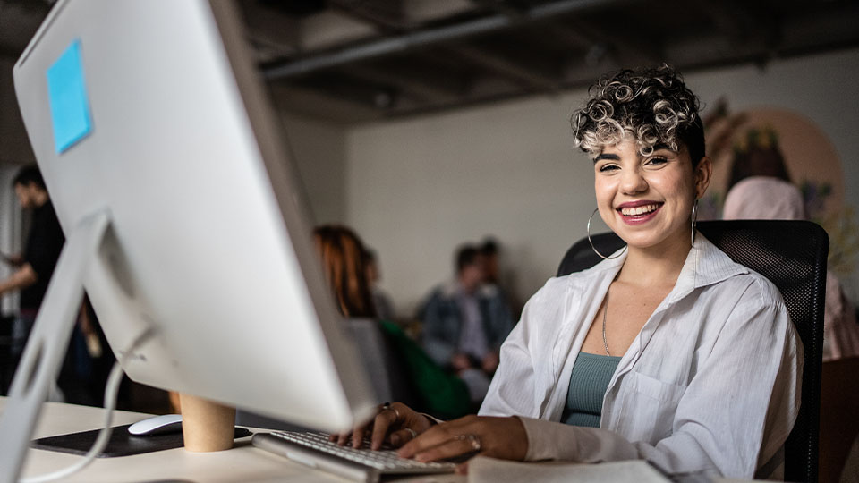 a lady looking at camera in front of computer